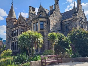 An image of an old building with a spire in the background and palm trees in the foreground.