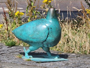 A large copper pigeon statue (maybe a foot and a half high). It's copper has turned green with patina.