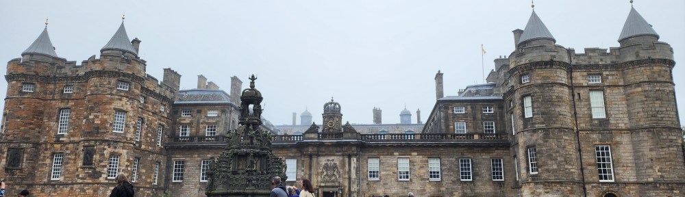 A full frontal view of Holyrood Palace with a statue in the front