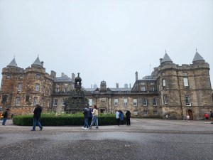 A full frontal view of Holyrood Palace with a statue in the front