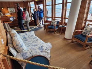 A cozy couch and rocking chairs with blue print design on the entrance into the ship