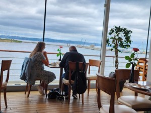 A couple sit at a table overlooking the water in the tearoom