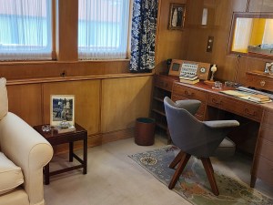 A room with brown paneling with a white easy chair, a gray desk chair and a desk. This was the Prince's office.