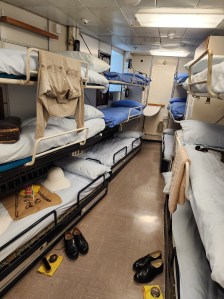 A thin tiny room with twelve bunks for crew (6 on each side)