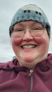 A large woman wearing a blue knitted cap smiles into the camera.