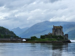 A distant shot of Eilean Donan castle; you can see the bridge that crosses over the loch to the island.  Low-lying clouds hang in the mountains.