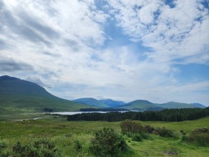 A landscape of a distant loch with mostly blue sky and some mountains
