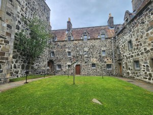 Three walls of Duart castle surround a grassy courtyard.