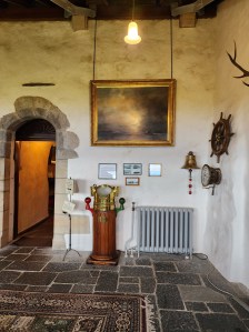 The Sea Room of Duart Castle, showing a large bell, wheel, and binnacle from the RMS Lochinvar ship. To the left is the entrance into the Great Hall.
