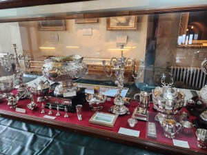 A glass case filled with silver soup tureens and pitchers at Duart Castle