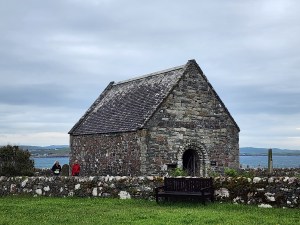 A small chapel with a stone wall in front of it. This is St. Oran's chapel at Iona Abbey