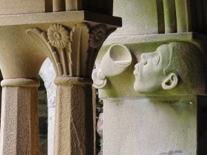 A detail from the cloisters of a man's head about to drink from Jesus's cup.
